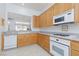 Functional kitchen with light wood cabinets, white appliances, and a pass-through window to the living room at 10300 Pinto Creek Ln, Las Vegas, NV 89144