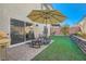 Backyard featuring an umbrella, patio, and artificial grass at 10393 Rose Palisade St, Las Vegas, NV 89141