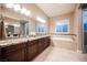 Bathroom featuring dual sinks, granite countertops, and a soaking tub at 10507 Bryn Haven Ave, Las Vegas, NV 89135