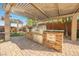 Outdoor kitchen with stainless grill, stone accents and ample counter space under a bright pergola at 10507 Bryn Haven Ave, Las Vegas, NV 89135