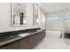 Bright bathroom showcasing a double vanity, freestanding tub, elegant mirrors, and a seamless glass shower at 1057 Giovanni Ln, Henderson, NV 89012