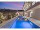 Twilight view of the luxurious backyard pool and spa with modern design and privacy fencing at 1057 Giovanni Ln, Henderson, NV 89012