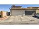 Two-car garage with a driveway needing some repair work and exterior with a stucco finish in need of some TLC at 1228 Mews Ln, Las Vegas, NV 89101