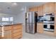 Open kitchen with wood cabinets, stainless steel fridge and double ovens, and granite counters at 1270 Del Lilly Ln, Las Vegas, NV 89123