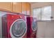 Bright laundry area featuring red Electrolux washer and dryer with wood cabinets above at 1270 Del Lilly Ln, Las Vegas, NV 89123