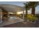 Relaxing backyard with a pool, covered patio, desert landscaping, and palm trees at 1657 Hartley Ave, Henderson, NV 89052