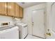 Bright laundry room with front loading washer and dryer and upper wooden cabinets at 1808 Scenic Sunrise Dr, Las Vegas, NV 89117