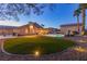 Spacious backyard with a well-manicured lawn, mature trees, and outdoor lighting at 4690 Designer Way, Las Vegas, NV 89129
