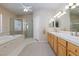 Bathroom featuring a soaking tub, glass-enclosed shower, and dual sink vanity at 4690 Designer Way, Las Vegas, NV 89129