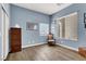 Blue bedroom with hardwood floors, a decorative chair, and natural light from the windows at 6392 Ebony Legends Ave, Las Vegas, NV 89131