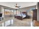 Spacious main bedroom with a dark wood bed frame, ceiling fan, and ample natural light from the windows at 6392 Ebony Legends Ave, Las Vegas, NV 89131