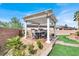 Backyard with a covered pergola seating area with lush green landscaping at 6392 Ebony Legends Ave, Las Vegas, NV 89131