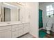 Bathroom with double sinks, a toilet, and a shower with a green patterned shower curtain at 683 Quasi St, Henderson, NV 89011