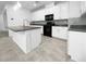 Modern kitchen featuring white cabinetry, black appliances, granite countertops, and a stylish tile backsplash at 7059 Mackenzie Bay Ave, Las Vegas, NV 89179