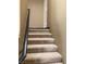 Carpeted staircase featuring a dark handrail leading to the upper level at 8777 W Maule Ave # 2167, Las Vegas, NV 89148