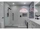 Modern bathroom with a tiled shower, rain shower head, half-moon window, and a white marble vanity at 9680 Granite Gorge Ct, Las Vegas, NV 89148