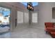 Bright living room with light-colored marble floors, modern light fixture, and view of the pool through sliding glass door at 9680 Granite Gorge Ct, Las Vegas, NV 89148