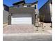 Contemporary two-story home with a gray facade, white garage door, and brick paved driveway at 10012 River Corral St, Las Vegas, NV 89166