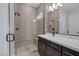 Modern bathroom with large glass shower, neutral tile, dark hardware and a large mirror above the sink at 10065 Auburn Rose Ave, Las Vegas, NV 89143