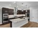 Modern kitchen features stainless appliances, granite counters, an island, pendant lighting, and dark wood cabinetry at 10065 Auburn Rose Ave, Las Vegas, NV 89143