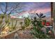 Relaxing backyard featuring desert landscaping, brick patio and seating area under a colorful sunset at 10532 Beachwalk Pl, Las Vegas, NV 89144