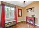 Bedroom with wood floor, a colorful chest, red side table, curtains, and a ceiling fan at 10532 Beachwalk Pl, Las Vegas, NV 89144