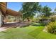 Spacious backyard featuring a covered patio, lush lawn, a charming garden with flowers and trees at 2233 Marlboro Dr, Henderson, NV 89014