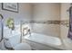 Bathroom featuring a tub with tile surround, grab bar, and toilet with green plants at 2233 Marlboro Dr, Henderson, NV 89014