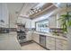 Well-lit kitchen features stainless steel appliances, light countertops, white cabinets and an open window at 2233 Marlboro Dr, Henderson, NV 89014