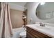 A well-lit bathroom features a shower-tub combo, a sink with wooden cabinets, and a mirror at 3212 Osage Ave, Las Vegas, NV 89101