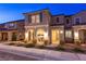 Warm home exterior at night, highlighting the cozy arched porch and landscape lighting at 3732 Via Gennaro, Henderson, NV 89044