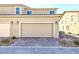 Two-car garage with brick-paved driveway in front of beige two-story townhouse under blue sky at 3732 Via Gennaro, Henderson, NV 89044