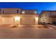 Two-car garage with brick-paved driveway in front of beige two-story townhouse at dusk at 3732 Via Gennaro, Henderson, NV 89044