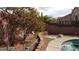 Landscaped backyard with a brick retaining wall, rocks and decorative trees surrounding the pool at 4798 Luna Ridge Ct, Las Vegas, NV 89129