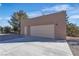 A detached garage with a large paved driveway with desert landscaping and a blue sky in the background at 5841 Doubletree Rd, Pahrump, NV 89061