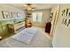 Bright Bedroom features a ceiling fan, carpet, window, and a crib, creating a cozy atmosphere for a baby's room at 6145 Scarlet Leaf St, Las Vegas, NV 89148