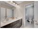 Bathroom with dual sinks, dark cabinetry, modern lighting, and a separate toilet area at 6221 Desert Orchid Way, Las Vegas, NV 89141