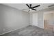 Neutral bedroom with a ceiling fan, gray carpet, white door, and access to the hallway at 6221 Desert Orchid Way, Las Vegas, NV 89141