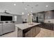 Open kitchen with stainless steel appliances, dark cabinetry, and a granite island, adjacent to the living area at 6221 Desert Orchid Way, Las Vegas, NV 89141