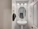 Stylish powder room with a pedestal sink, decorative mirror, and contemporary fixtures at 6221 Desert Orchid Way, Las Vegas, NV 89141