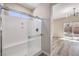 A sleek, glass-enclosed shower with a bench is adjacent to a bedroom with wood-look floors and backyard access at 7315 Summer Air Ave, Las Vegas, NV 89179