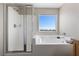 Bright bathroom featuring a tiled shower, soaking tub, and a window with a scenic view at 8124 Loma Del Ray St, Las Vegas, NV 89131