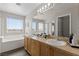 Bright bathroom with double sinks, wood cabinets, soaking tub and large mirror reflecting the shower at 8124 Loma Del Ray St, Las Vegas, NV 89131