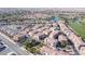 Expansive aerial view of a vibrant community with red tile roofs and lush landscaping, near a golf course and lake at 1040 Via Panfilo Ave, Henderson, NV 89011