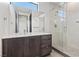 Modern bathroom featuring a sleek vanity with dark wood cabinets, large mirror, and glass-enclosed shower at 14 Heron Harbour Dr, Henderson, NV 89011