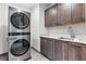 Modern laundry room equipped with a stainless steel washer and dryer, with dark wood cabinetry at 14 Heron Harbour Dr, Henderson, NV 89011