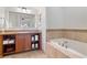 Well-lit bathroom featuring a soaking tub, tile accents, and ample storage space in wooden cabinets at 21 Via Visione # 201, Henderson, NV 89011