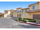 A sunny view of a multi-unit stucco home with garages, tidy landscaping, and ample parking at 21 Via Visione # 201, Henderson, NV 89011