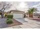 Home exterior with a wide driveway, a two-car garage, desert landscaping, and healthy green shrubs at 2125 Desert Woods Dr, Henderson, NV 89012