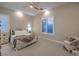 Neutral bedroom with a ceiling fan, two windows, and a cozy seating area at 24 Cliffwater St, Henderson, NV 89011